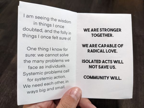 The left page of a zine reads: I am seeing the wisdom in things I once doubted, and the folly in things I once felt sure of. One thing I know for sure: we cannot solve the many problems we face as individuals. Systemic problems call for systemic action. We need each other, in ways big and small. The right reads: We are stronger together. We are capable of radical love. Isolated acts will not save us. Community will.