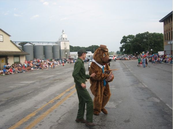 a person in a park ranger uniform talks to a person in a bear costume