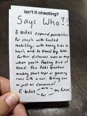 the back of a zine, it reads: Isn't it cheating? Says who?? E-bikes expand possibilities- for people with limited mobility, with heavy kids to haul, and to travel by bike farther distances even on days when you're feeling kind of tired. Few folks question making short trips or grocery runs with a car. Biking can be just as convenient. E-bikes are the future, e-bikes for the future.